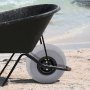 wheelbarrow with VEVOR beach balloon wheels on sandy shore near ocean waves.