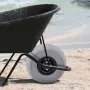 wheelbarrow with VEVOR beach balloon wheels on sandy shore near ocean waves.
