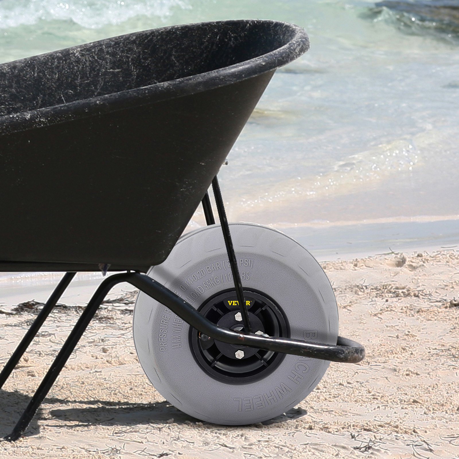 wheelbarrow with VEVOR beach balloon wheels on sandy shore near ocean waves.