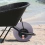 wheelbarrow with VEVOR beach balloon wheels on sandy beach with ocean waves in the background.