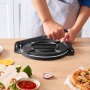 person using a VEVOR tortilla press on a wooden table with wraps, salsa, and pizza nearby.
