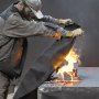 worker using VEVOR welding blanket to cover a fire on a metal surface, showcasing heat resistance.