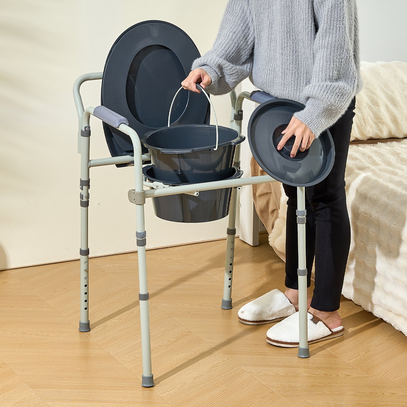 person assembling VEVOR commode chair beside a bed, holding a bucket and lid, showcasing its functionality.