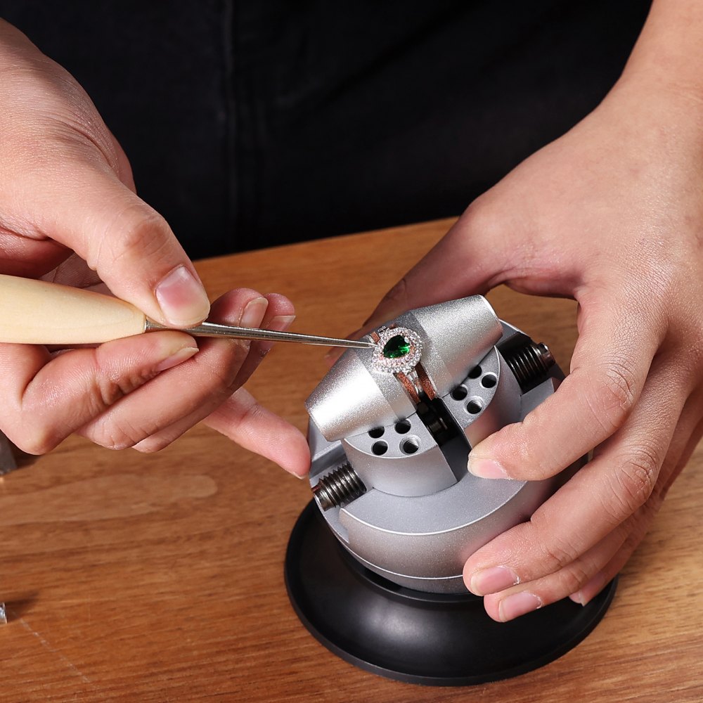 crafting jewelry using the VEVOR ball vise on a wooden table, focusing on a ring with a green gemstone.
