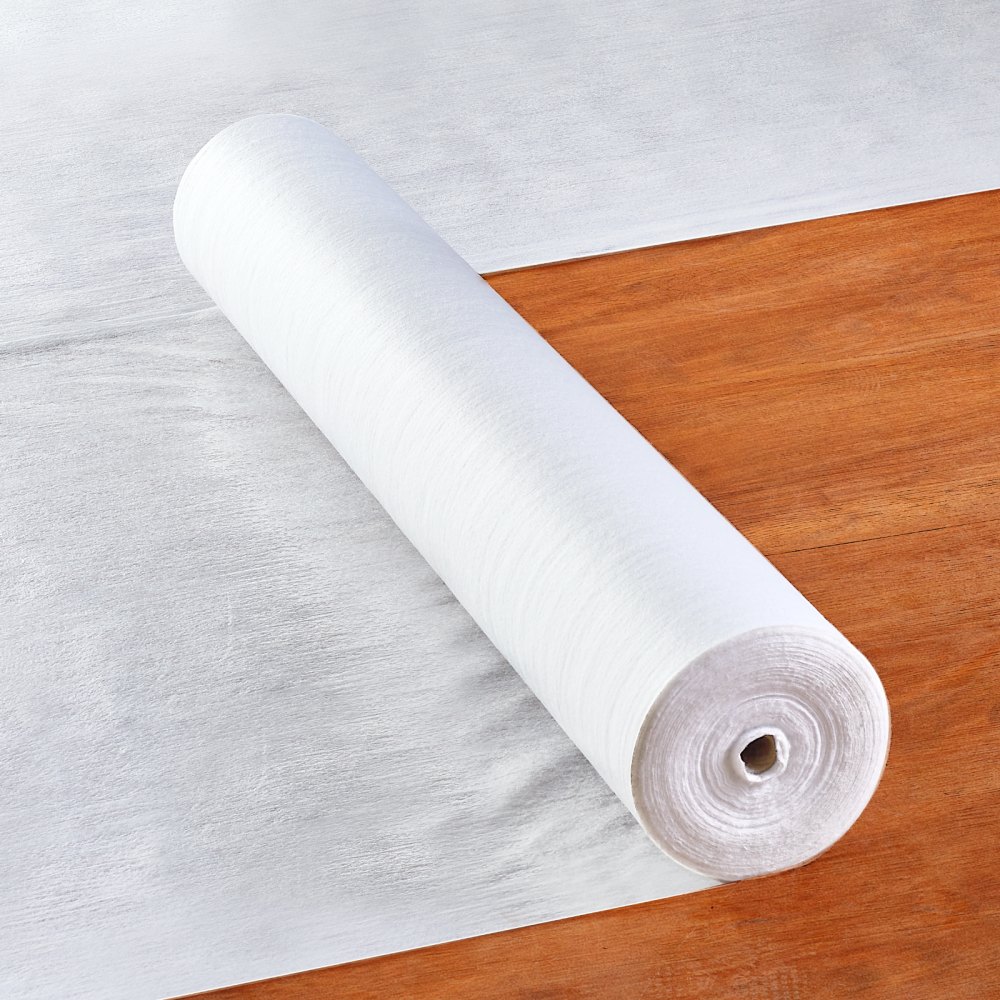 roll of VEVOR carpet protection film on a wooden floor extending onto a white sheet.