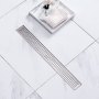 VEVOR linear shower drain on white marble tile floor with a tray, soap, and flowers nearby.