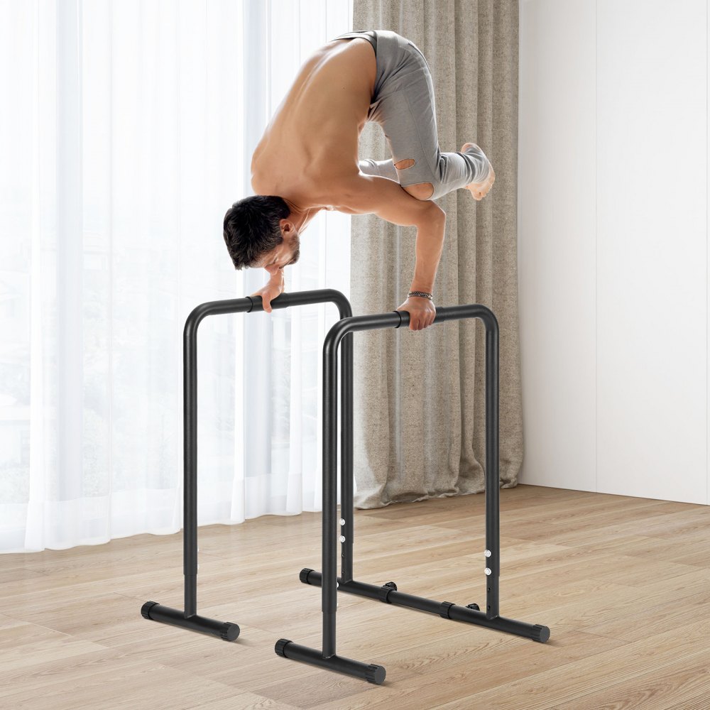 man performing exercise on VEVOR dip bar in a bright room with wooden flooring and curtains.