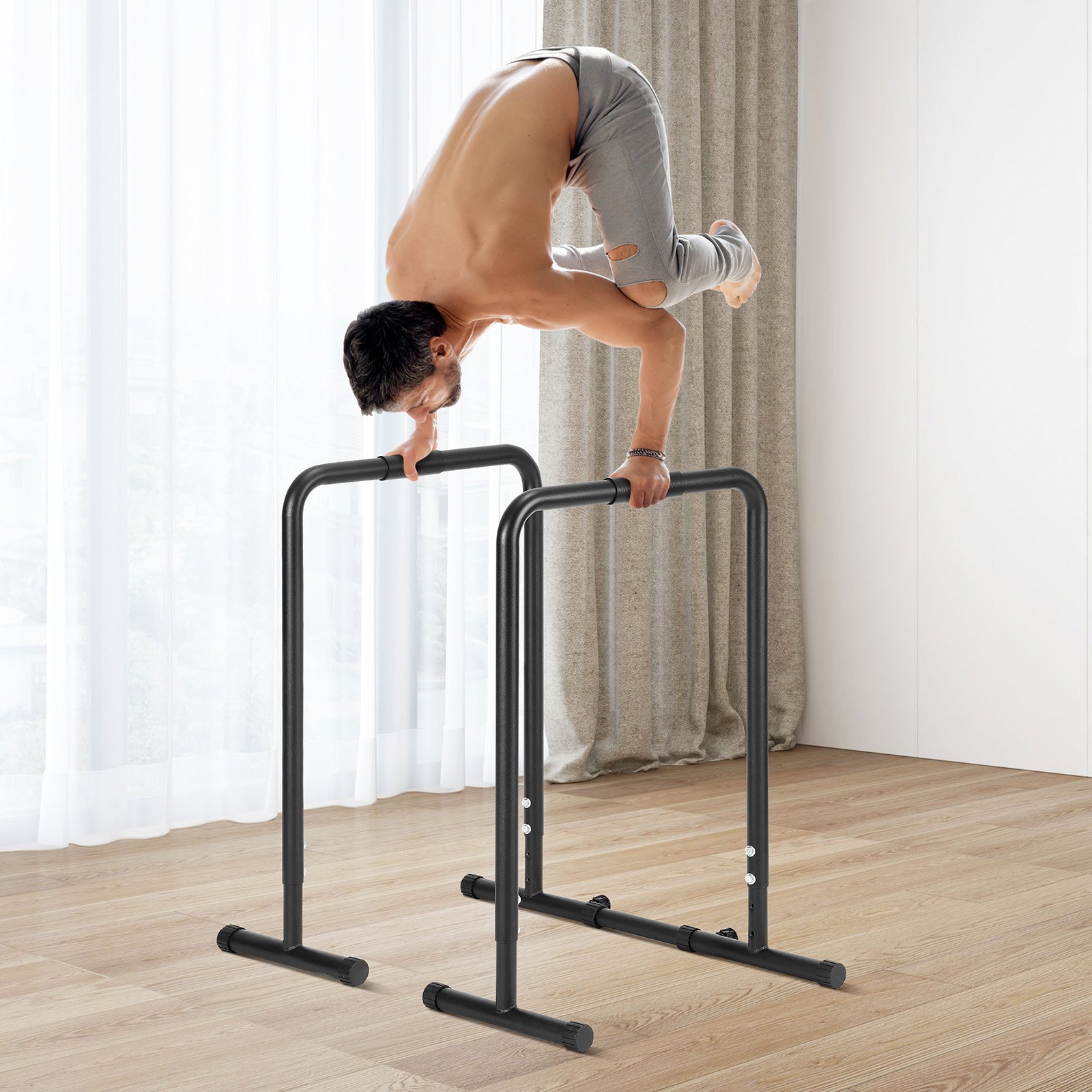 man performing exercise on VEVOR dip bar in a bright room with wooden flooring and curtains.