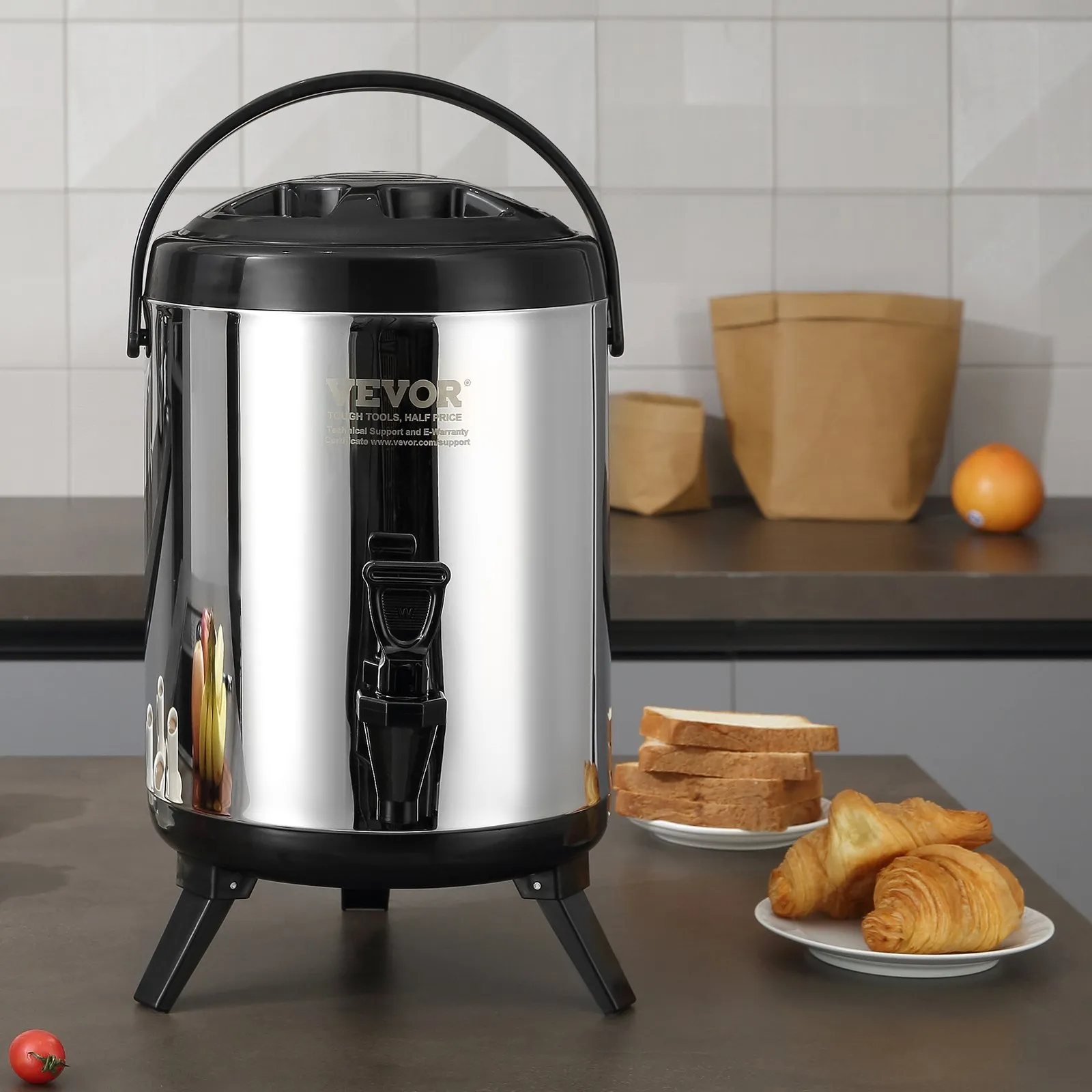 VEVOR stainless steel beverage dispenser on a kitchen counter with bread and croissants nearby.