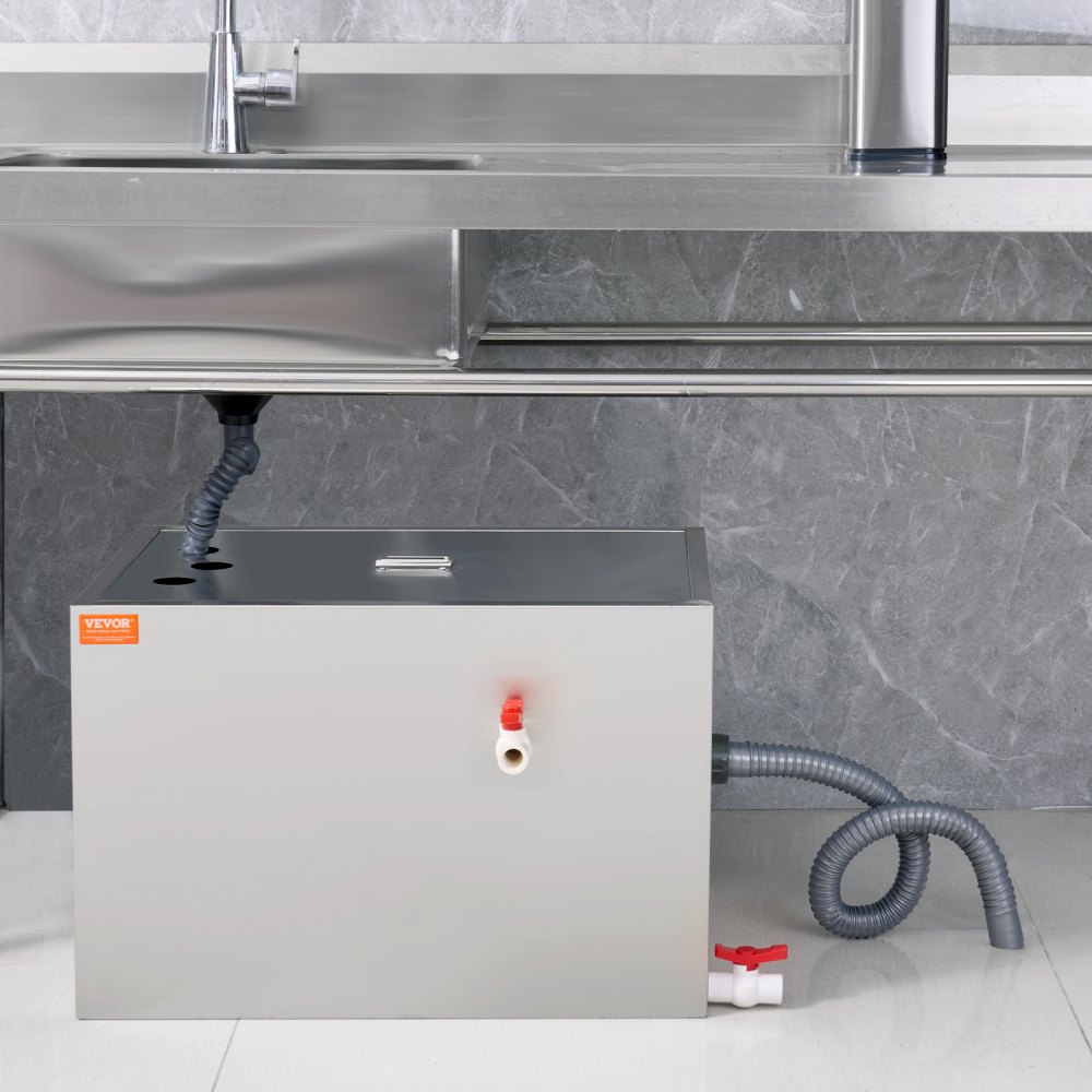 VEVOR grease trap installed under a stainless steel kitchen sink with gray tiled wall background.