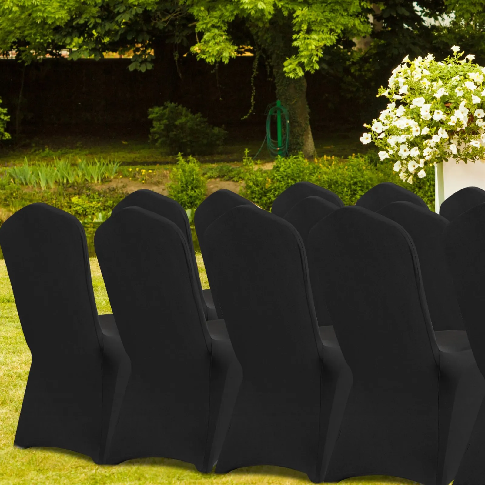 black VEVOR chair covers on outdoor chairs in a garden setting with green foliage and white flowers.