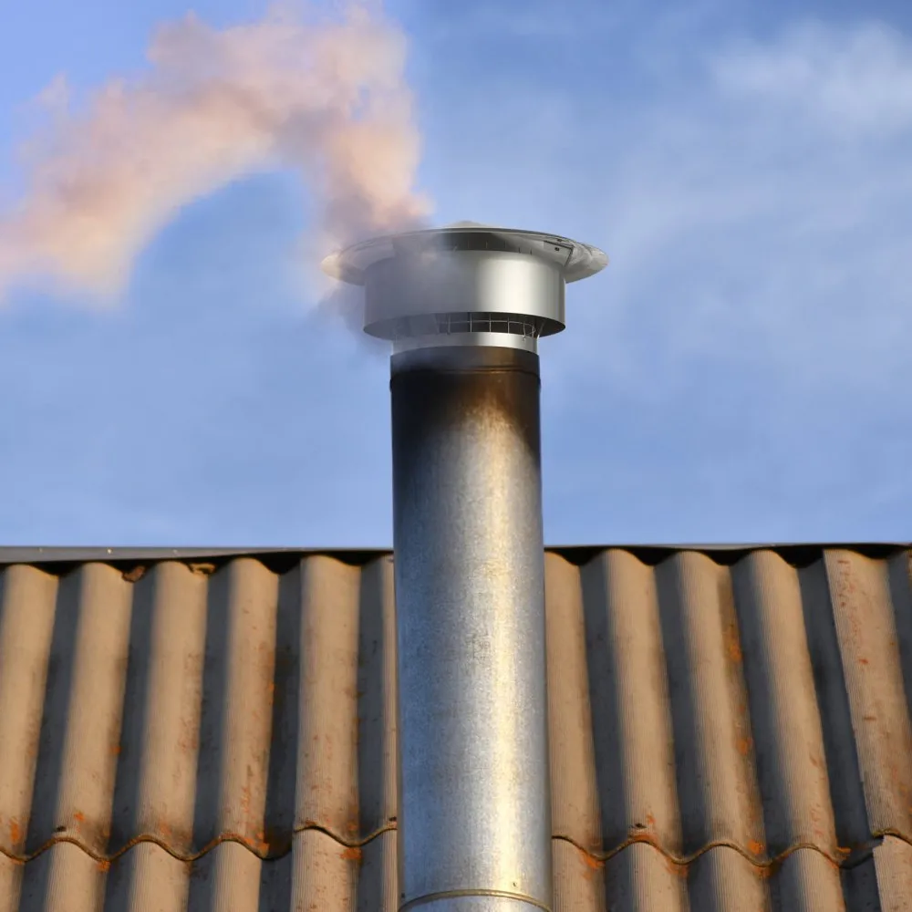 metal chimney with VEVOR chimney cap releasing smoke above a corrugated rooftop against a clear sky.