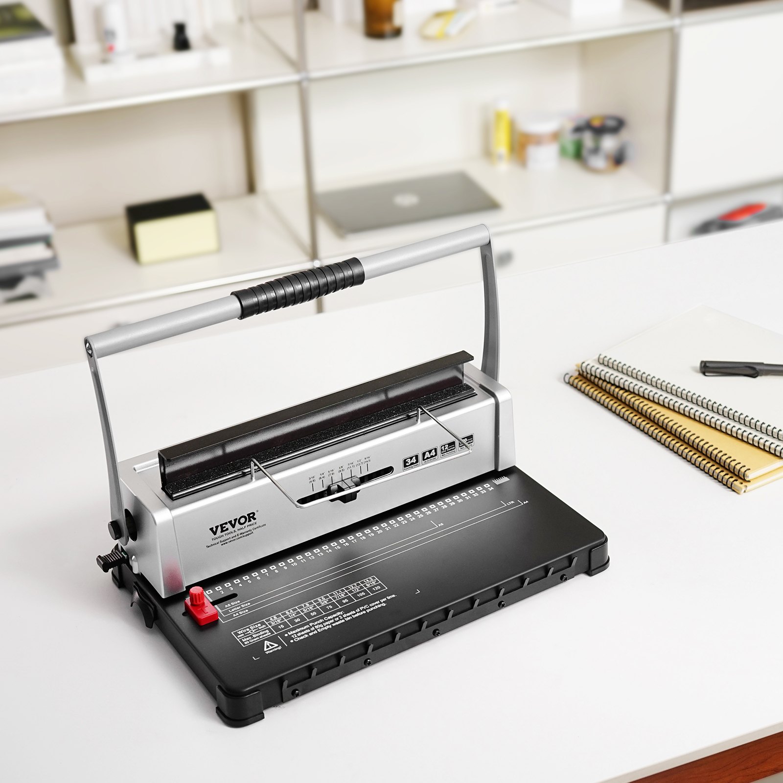 VEVOR binding machine on a white desk with notebooks and shelves in the background.