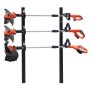 three orange trimmers neatly organized on a black VEVOR trimmer rack with securing locks attached.