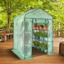 VEVOR walk-in greenhouse, plants in pots inside, on a wooden deck surrounded by lush greenery.