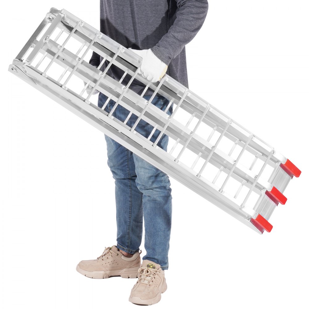 person holding a folded VEVOR motorcycle loading ramp with red-tipped ends, wearing jeans and sneakers.