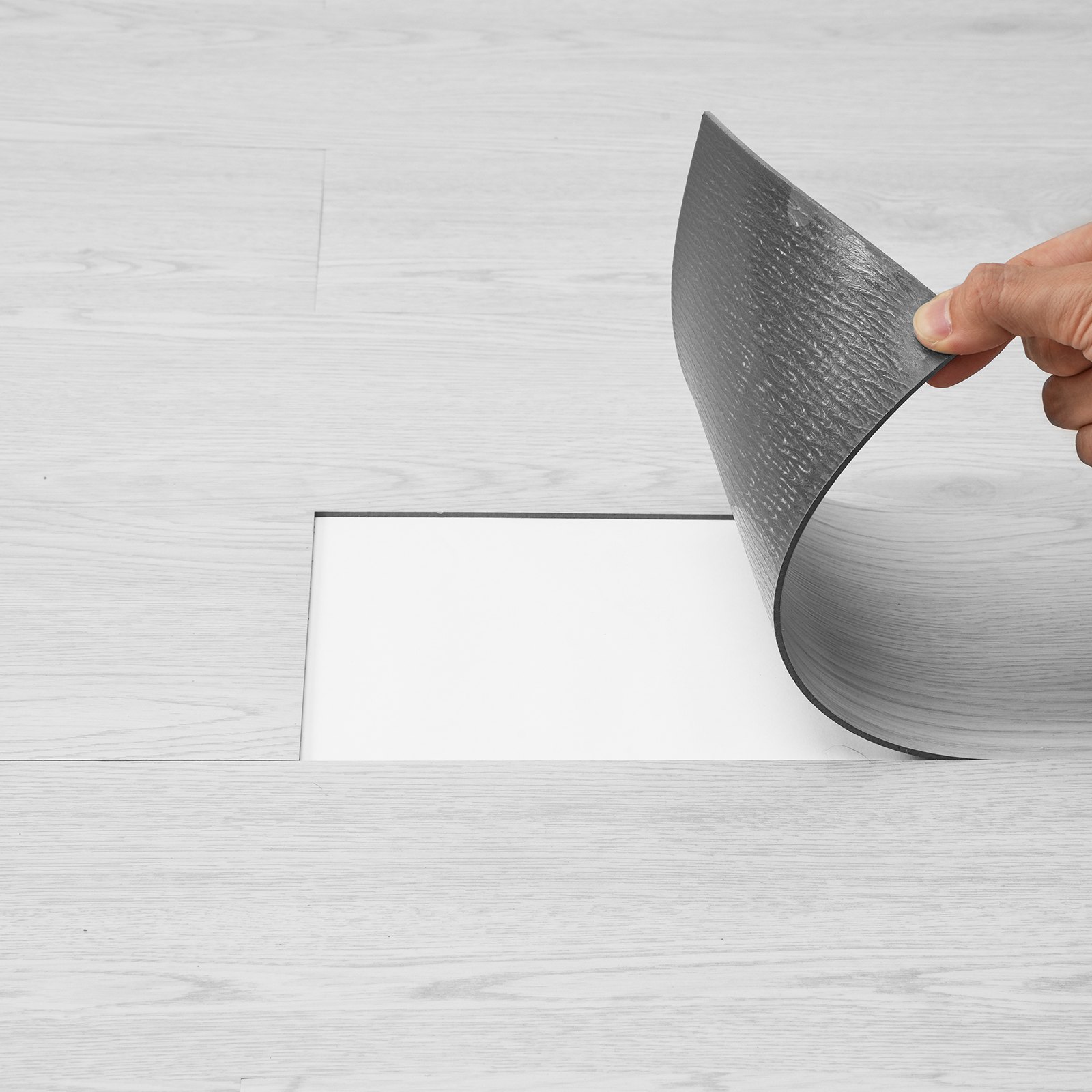 hand installing VEVOR vinyl floor tiles on light wood flooring.