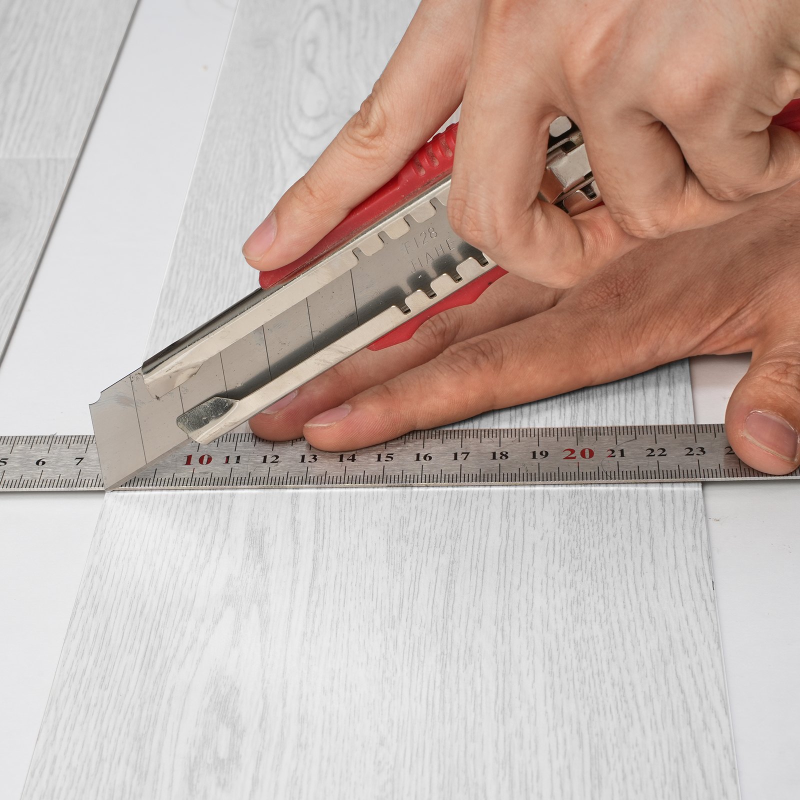 cutting VEVOR vinyl floor tiles with precision using a utility knife and ruler.