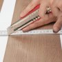 cutting VEVOR self adhesive vinyl floor tiles with a utility knife and measuring tape.